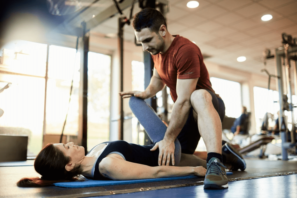 fisioterapeuta deportivo entrenando a una paciente en el gimnasio
